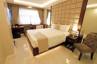 a bedroom with a bed and a desk and a chair at Monaco Hotel in Taytay
