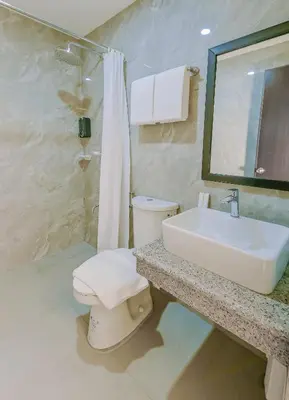 a bathroom with a white toilet and a sink at Monaco Hotel in Taytay
