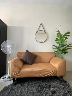 a brown leather couch in a living room with a fan at Mountain View at Beacon Tower in Manila