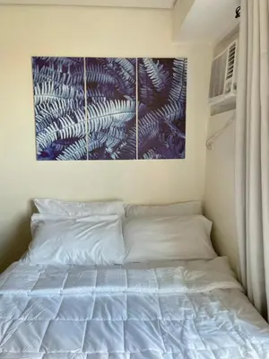 a bed in a bedroom with a painting on the wall at Mountain View at Beacon Tower in Manila