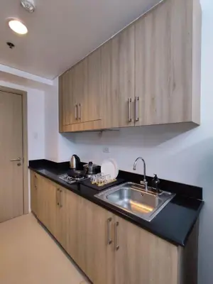 a kitchen with a sink and wooden cabinets at Shatze's Place-One Bedroom Pool view near MOA and Airport in Manila