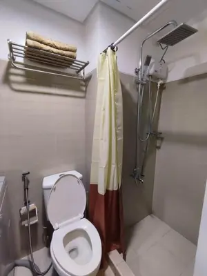 a bathroom with a toilet and a shower at Shatze's Place-One Bedroom Pool view near MOA and Airport in Manila