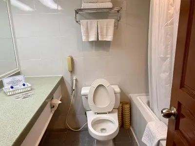 a small bathroom with a toilet and a phone at Maharaja Oriental Suite Makati in Manila