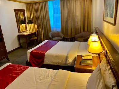 a hotel room with two beds and a table at Maharaja Oriental Suite Makati in Manila