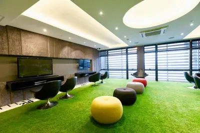 a room with green carpet and chairs and a television at Kaiyana Apartments in Manila