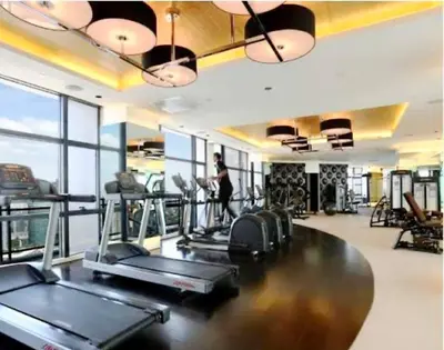 a gym with several treadmills and a woman in the background at Kaiyana Apartments in Manila