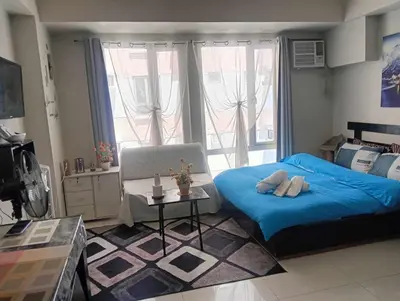 a bedroom with a blue bed and a window at Ilustrata Residences Condominium in Manila