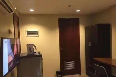 a room with a television and a door with a microwave at Spacious Studio Apartment B302 in Manila