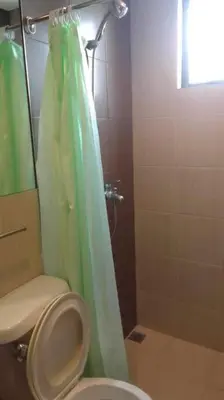 a bathroom with a green shower curtain and a toilet at Spacious Studio Apartment B304 in Manila