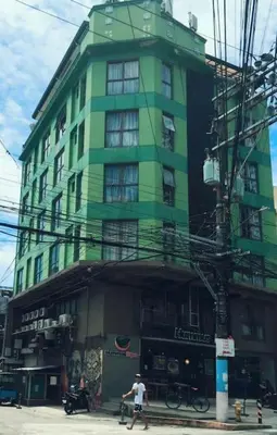 a green building with a man walking in front of it at Spacious Studio Apartment B306 in Manila