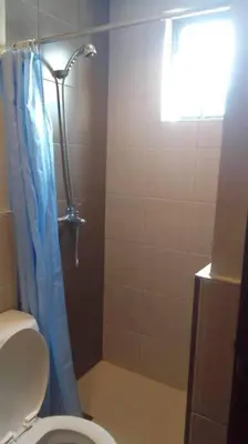 a bathroom with a shower with a toilet and a blue shower curtain at Spacious Studio Apartment B306 in Manila