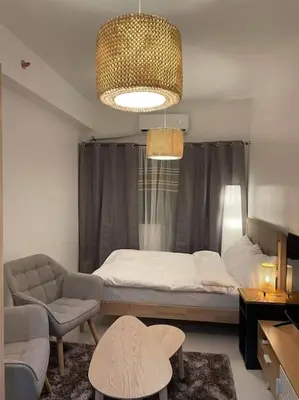 a bedroom with a bed and a chair and a couch at House KubU at Lush Residences Makati in Manila