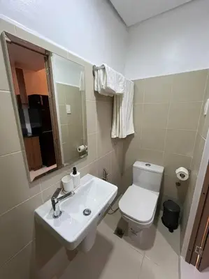 a bathroom with a white toilet and a sink at House KubU at Lush Residences Makati in Manila