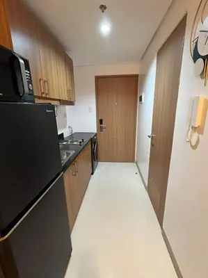 a kitchen with a black refrigerator and a sink at House KubU at Lush Residences Makati in Manila