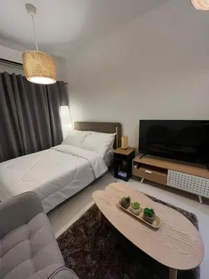 a bedroom with a bed and a tv and a couch at House KubU at Lush Residences Makati in Manila