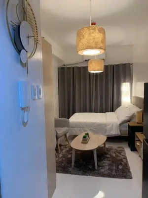 a bedroom with a bed and a table in a room at House KubU at Lush Residences Makati in Manila