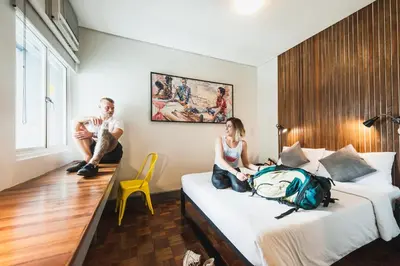 a man and woman sitting on beds in a hotel room at Z Hostel in Manila