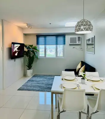 a dining room with a table and chairs and a tv at Cozy Minimalist 2BR Condo at Princeton QC near Rob Magnolia in Manila