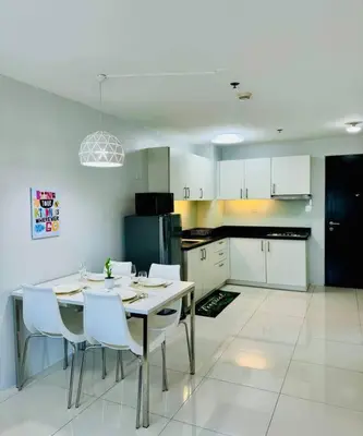a kitchen with a table and white chairs in it at Cozy Minimalist 2BR Condo at Princeton QC near Rob Magnolia in Manila