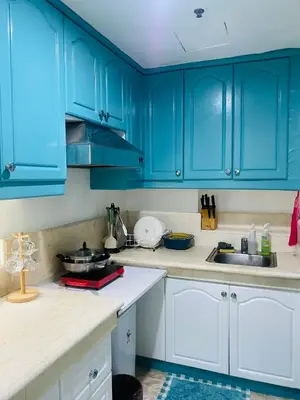 a blue kitchen with white cabinets and a sink at Baywatch Tower in Manila