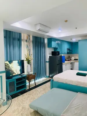a room with a bed and a kitchen with blue cabinets at Baywatch Tower in Manila