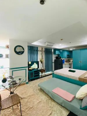 a bedroom with a large bed and a living room at Baywatch Tower in Manila