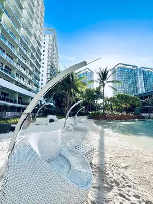 a beach with a white chair and some buildings at The Solaris Point with Pool View in Manila
