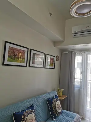 a living room with a blue couch and a window at Mall of Asia condotel in Manila