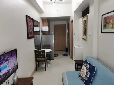 a living room with a blue couch and a kitchen at Mall of Asia condotel in Manila