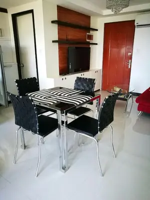 a dining room table with black chairs and a television at ADB AVENUE TOWER in Manila