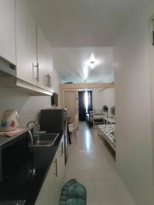 a kitchen with a sink and a room with two beds at 1BR SEA RESIDENCE by ABBY in Manila