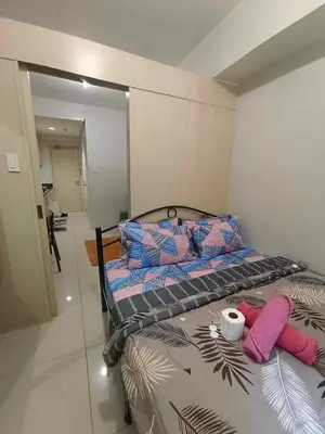 a bedroom with a bed with purple and blue pillows at 1BR SEA RESIDENCE by ABBY in Manila
