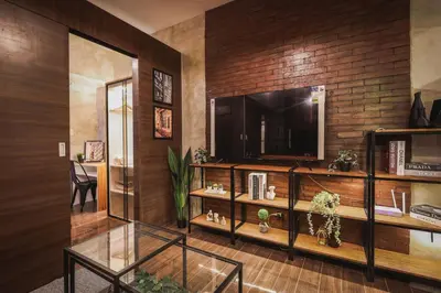 a living room with a television and a brick wall at Kensal Industrial - Air Residences in Manila