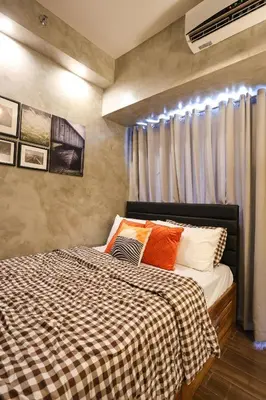 a bedroom with a bed with a checkered blanket at Kensal Industrial - Air Residences in Manila
