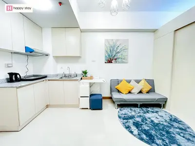 a kitchen with white cabinets and a couch and a rug at Happy Stay in Manila