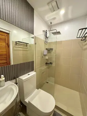 a bathroom with a toilet and a shower and a sink at Fullerton Suites in Puting Kahoy