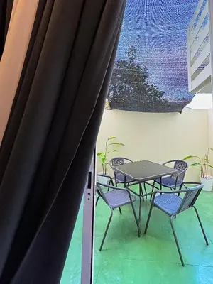 a table and chairs in a room with a curtain at Fullerton Suites in Puting Kahoy