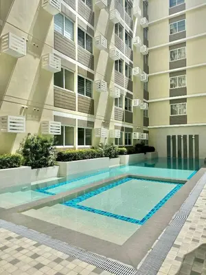 a swimming pool in front of a building at Fullerton Suites in Puting Kahoy