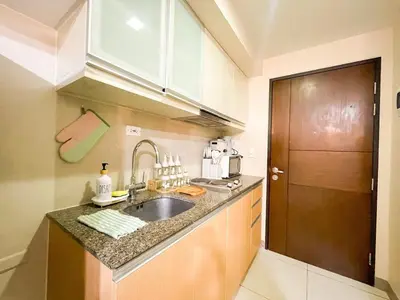 a kitchen with a sink and a wooden door at BGC Stay: Prime Condo AcrossGrand Hyatt #oursw32p in Manila