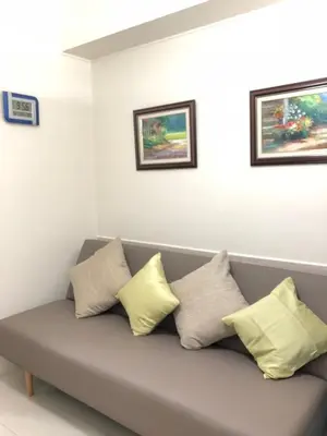 a couch with four pillows on it in a room at Sea Residences Holiday Rentals in Manila