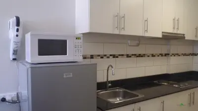 a kitchen with a microwave on top of a refrigerator at Sea Residences Holiday Rentals in Manila