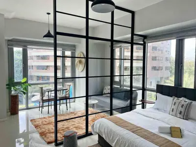 a bedroom with a large bed and a living room at Gora studio in Avant BGC parking with fee in Manila