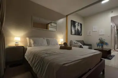 a bedroom with a large bed and a chair at #31 One Uptown Residences BGC in Manila