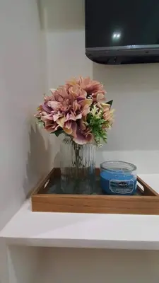 a vase filled with flowers sitting on a shelf at Luxury Condo with a view of Manila Bay in Manila