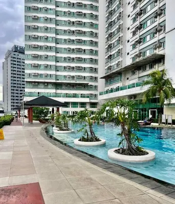 a swimming pool with palm trees in front of a large building at Modern 2BR in Central Makati! Netflix Wi-Fi Pool in Manila