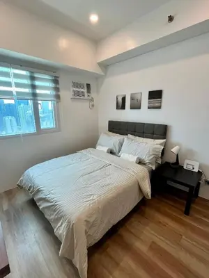 a bedroom with a large bed and a desk at Modern 2BR in Central Makati! Netflix Wi-Fi Pool in Manila