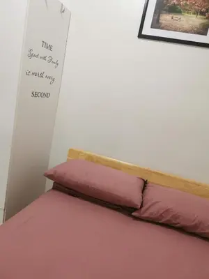 a bed with two pink pillows and a sign on the wall at Mall of Asia shore 3 tower 2 condotel in Manila