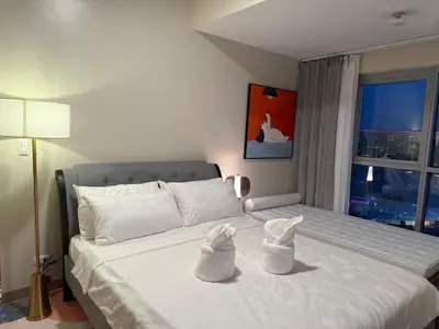 a bedroom with a large white bed with a window at Luxurious 1 Br Facing Manila Bay Sunset Nearby Okada MOA Solaire Ayala Malls in Manila