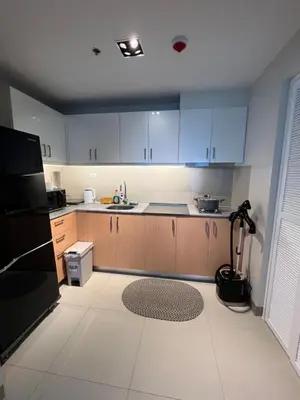 a kitchen with wooden cabinets and a black refrigerator at Luxurious 1 Br Facing Manila Bay Sunset Nearby Okada MOA Solaire Ayala Malls in Manila