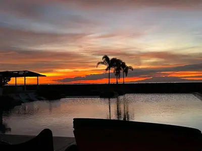 a sunset over a body of water with palm trees at Luxurious 1 Br Facing Manila Bay Sunset Nearby Okada MOA Solaire Ayala Malls in Manila